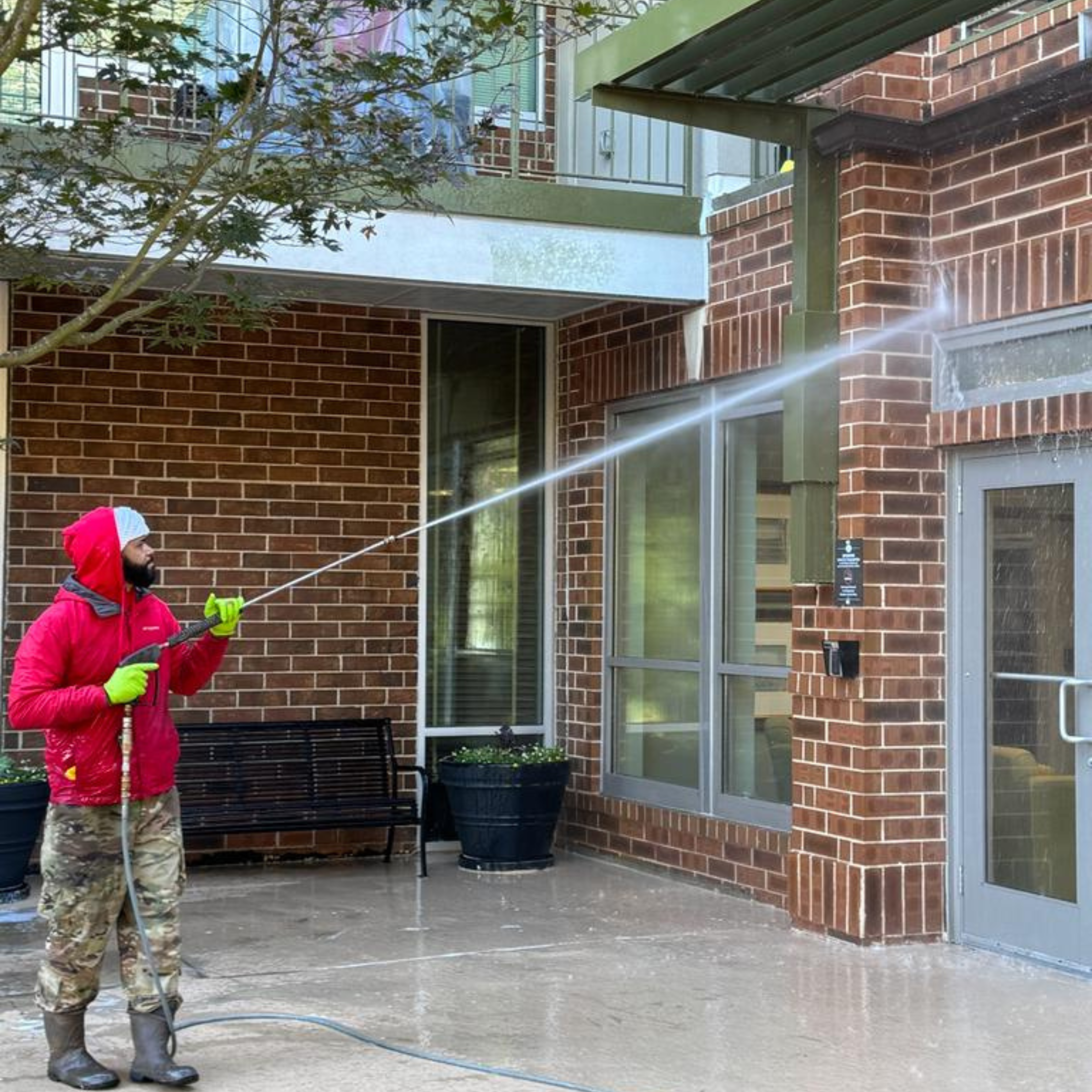 Man pressure washing a building exterior, removing dirt and grime for a refreshed, clean appearance.